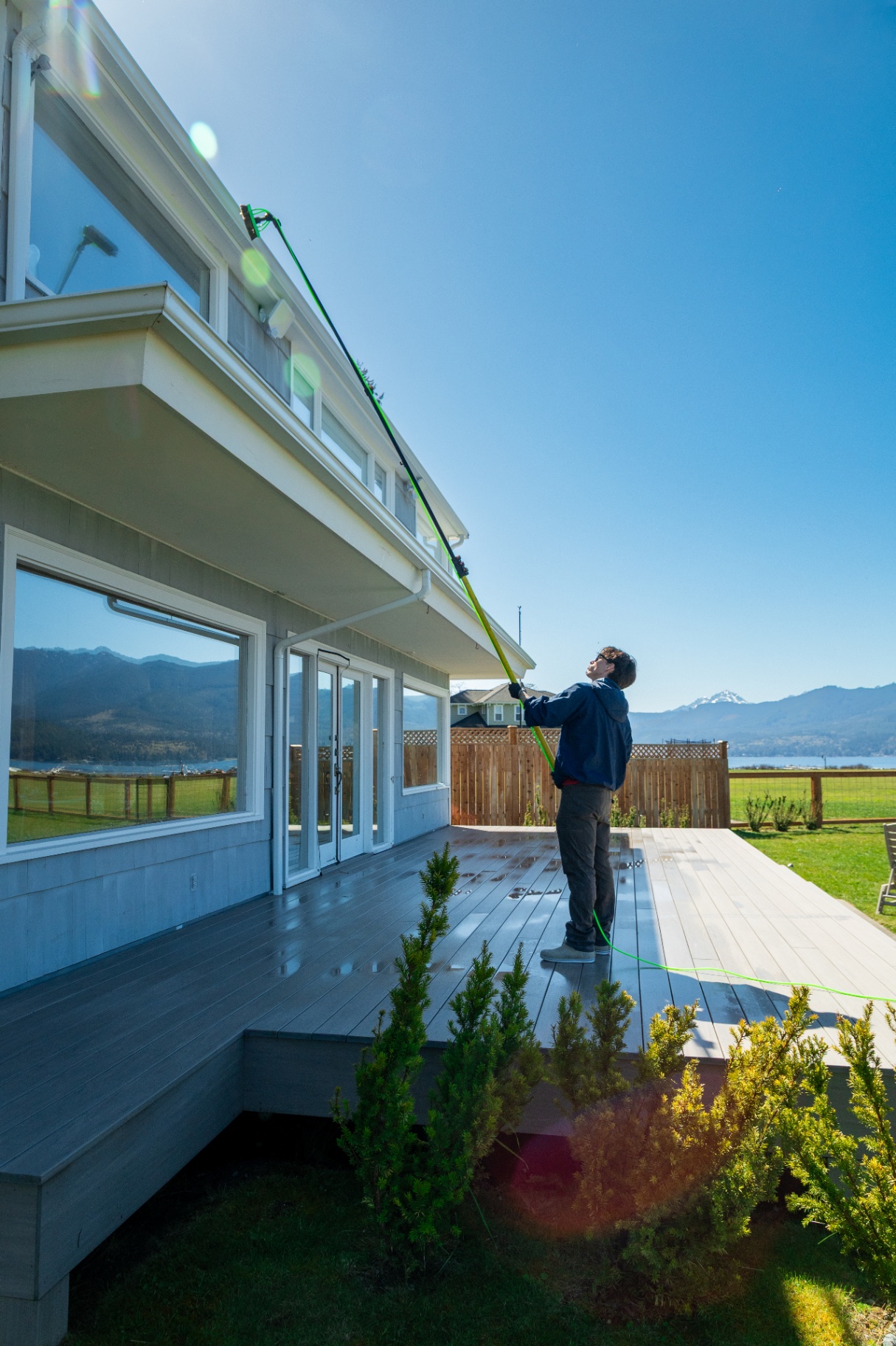 Sound Exterior Solutions technician cleaning residential windows with a water-fed pole in Kitsap County