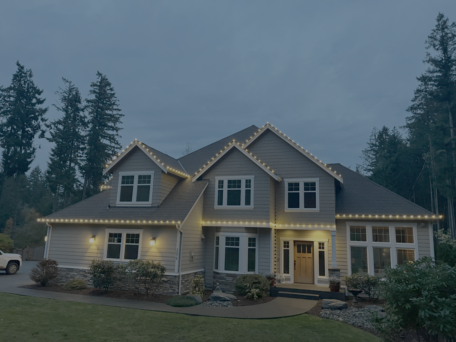 Two-story Kitsap County home with warm-white C9 Christmas lights along rooflines and dormers